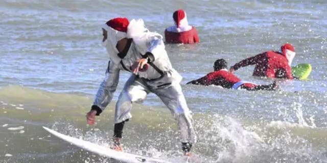 Surfer Corey Howell in a space man Surfing Santa suit, rides with waves with other surfing Santas for the 14th annual Surfing Santas of Cocoa Beach event Christmas Eve morning, Saturday, Dec. 24, 2022