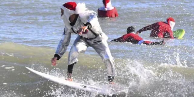 Surfer Corey Howell in a space man Surfing Santa suit, rides with waves with other surfing Santas for the 14th annual Surfing Santas of Cocoa Beach event Christmas Eve morning, Saturday, Dec. 24, 2022