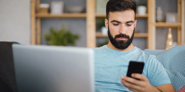 Man using laptop and on phone 