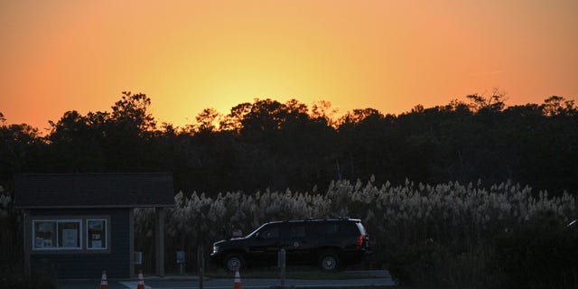 The SUV carrying President Biden is seen under a setting sun after Biden arrived at Gordons Pond in Cape Henlopen State Park in Lewes, Delaware, on Oct. 21, 2022.