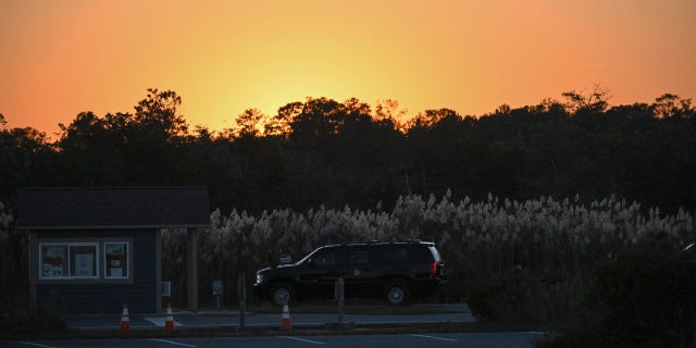 The SUV carrying President Biden is seen under a setting sun after Biden arrived at Gordons Pond in Cape Henlopen State Park in Lewes, Delaware, on Oct. 21, 2022.