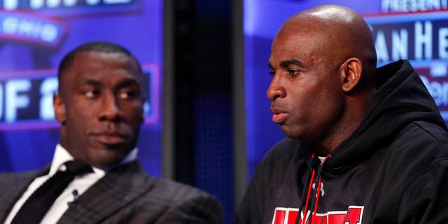 Deion Sanders speaks as Shannon Sharpe looks on after both were inducted into the 2011 Pro Football Hall of Fame class during an announcement at the Super Bowl XLV media center on February 5, 2011, in Dallas, Texas. 