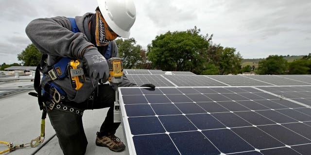 A worker installs a rooftop solar panel.