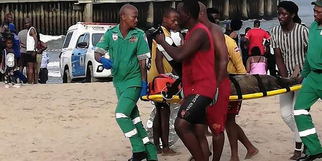 Paramedics carry an injured person on a stretcher on the Bay of Plenty Beach in Durban, South Africa, on Dec. 17, 2022