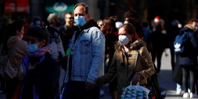 People wear protective face masks as they walk down a street in Madrid, Spain, on Feb. 7, 2022.