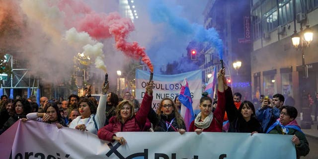 Demonstrators hold smoke flares during a protest against potential amendments to Spain's 'Trans Law' in Madrid, Spain, on Saturday, Dec. 10, 2022. 