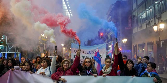 Demonstrators hold smoke flares during a protest against potential amendments to Spain's 'Trans Law' in Madrid, Spain, on Saturday, Dec. 10, 2022.