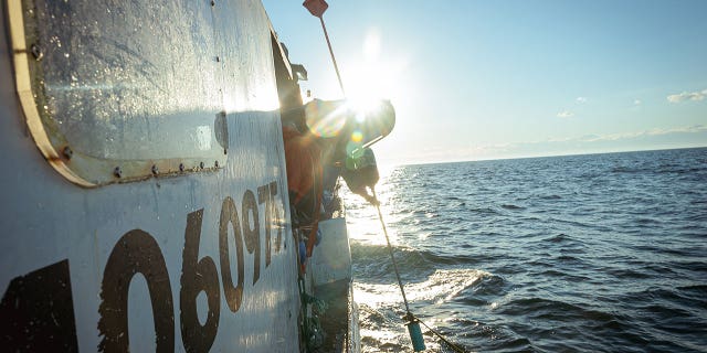 Crew members aboard a boat sailing in coastal Maine waters.