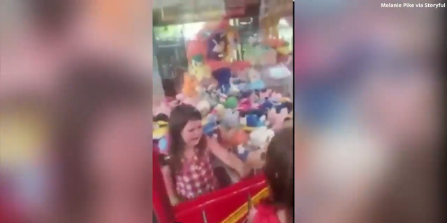 Poppy Pike, 4, is seen trapped inside a claw machine after apparently climbing through the swing door located at the bottom.