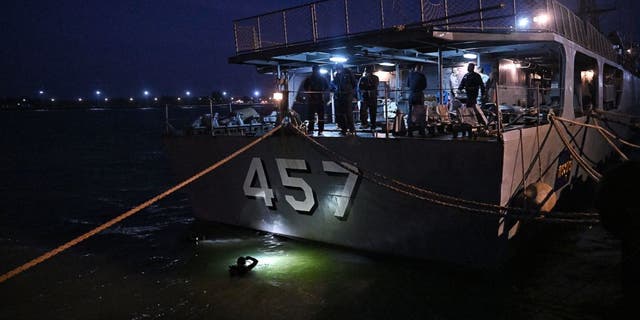 Navy divers inspect the hull of HTMS Kraburi docked at Bang Saphan Pier in Prachuap Khiri Khan on December 20, 2022, during the search operation for survivors after the Thai naval vessel HTMS Sukhothai capsized and sank about 37 kilometres (22 miles) off the coast on December 18. (LILLIAN SUWANRUMPHA/AFP via Getty Images)
