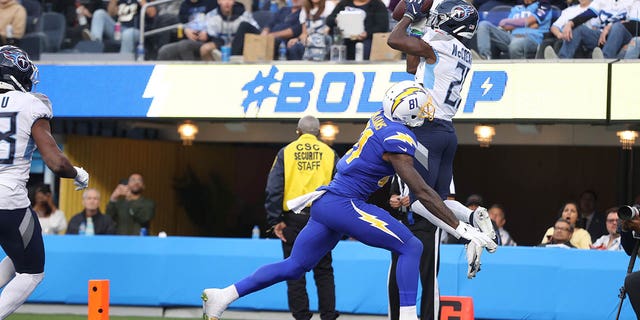 Roger McCreary #21 of the Tennessee Titans sends a pass intended for Mike Williams #81 of the Los Angeles Chargers to Joshua Kalu #28 of the Tennessee Titans for an interception during the second quarter at SoFi Stadium on December 18, 2022 in Inglewood, California.