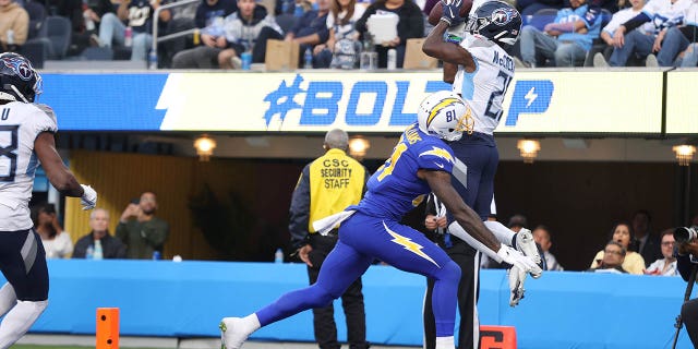 Roger McCreary #21 of the Tennessee Titans sends a pass intended for Mike Williams #81 of the Los Angeles Chargers to Joshua Kalu #28 of the Tennessee Titans for an interception during the second quarter at SoFi Stadium on December 18, 2022 in Inglewood, California.