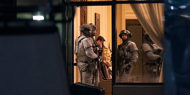 York Regional Police tactical officers stand in the lobby of a condominium building in Vaughan, Ontario, Sunday, Dec. 18, 2022. Police said multiple people are dead, including the suspect, after a shooting in a unit of the building.  