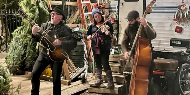 The Romp family of Vermont performs on Jane Street in Greenwich Village beside their Christmas tree stand, Dec. 13, 2022. From left, dad Billy, daughter Ellie and son Henry.