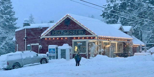 People shovel snow outside the Roma Grocery store northeast of Bellingham, Wash., on Tuesday morning. Heavy snow, freezing rain and sleet have disrupted travel across the Pacific Northwest, causing widespread flight cancellations and unsafe driving conditions.