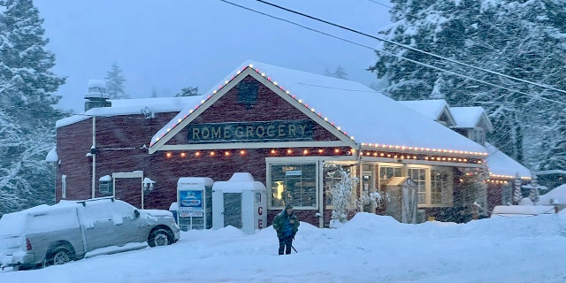 A person shovels snow outside Rome Grocery northeast of Bellingham, Washington, on Tuesday morning. Heavy snow, freezing rain and sleet have disrupted travel across the Pacific Northwest, causing widespread flight cancellations and creating hazardous driving conditions.