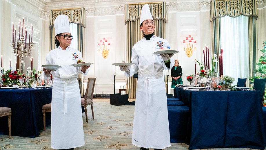 Chefs holding food on a plate.