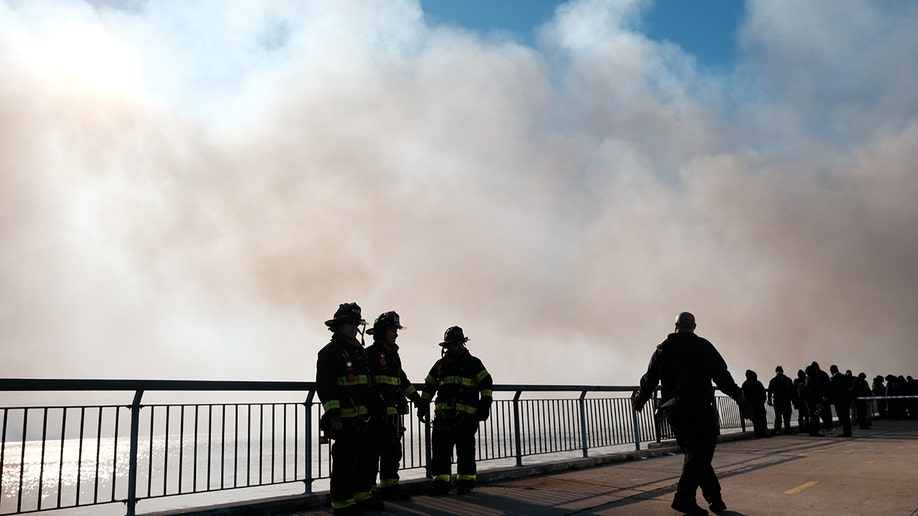 Firefighters under a plume of smoke
