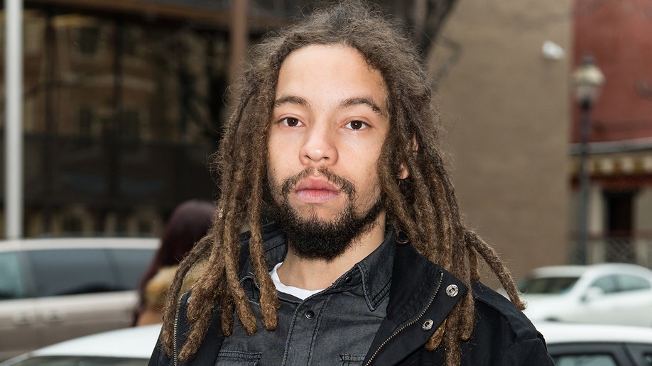 Joseph "Jo Mersa" Marley in a dark grey denim shirt and black jacket with dreadlocks