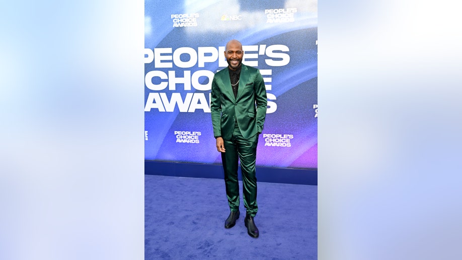 Karamo Brown wears shiny greenish  suit   connected  reddish  carpet astatine  People's Choice Awards