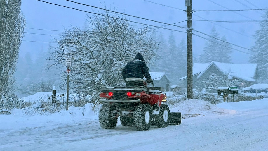 man riding four-wheeler through snow