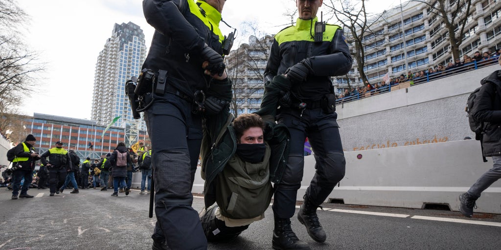 Climate change protesters in The Hague block highway, get detained and hauled away by bus