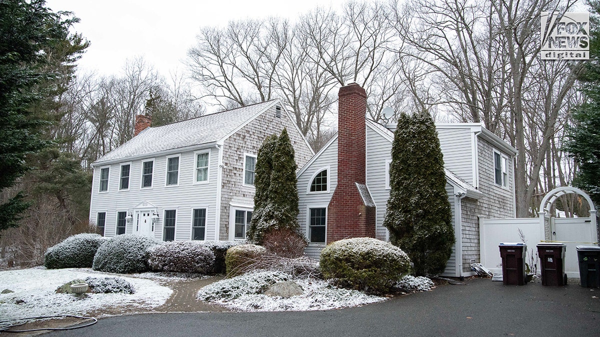 An exterior view of a white, two-story house covered in snow.