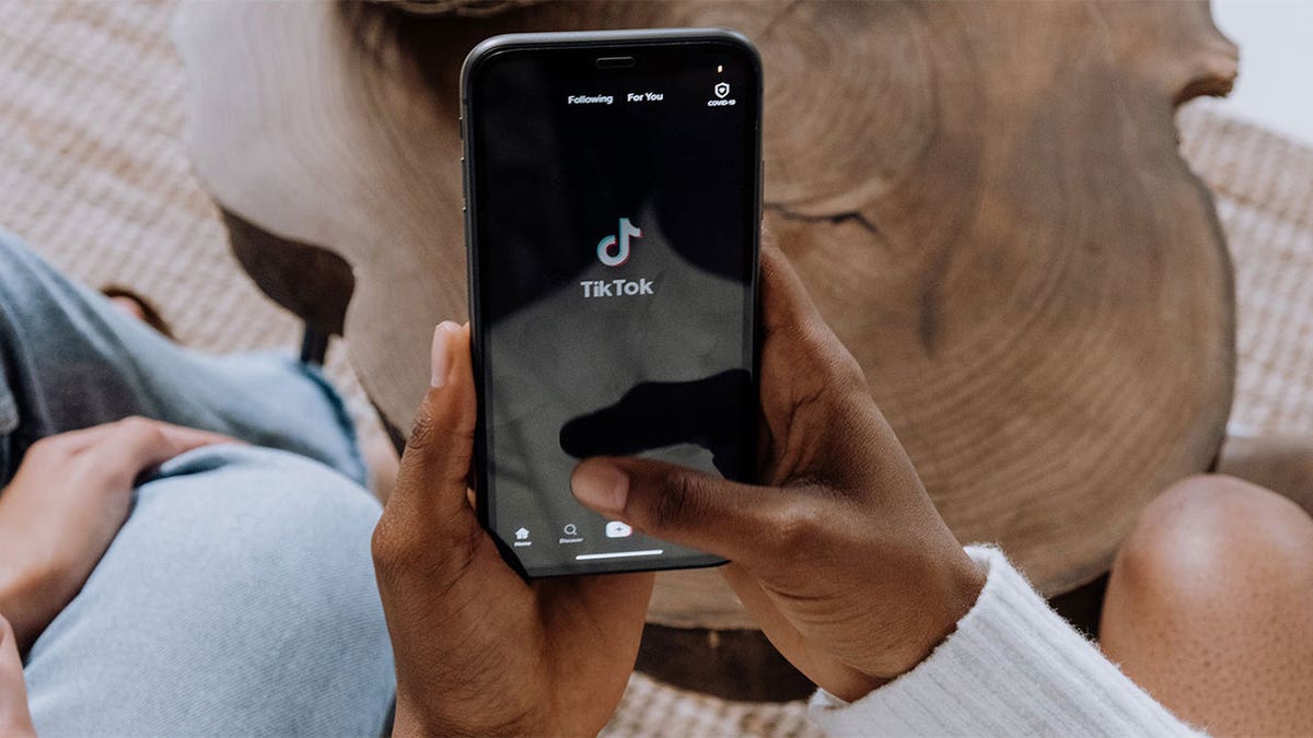 Photo of someone holding their phone, accessing TikTok.