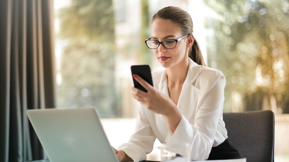 Woman looks at phone while working at an office