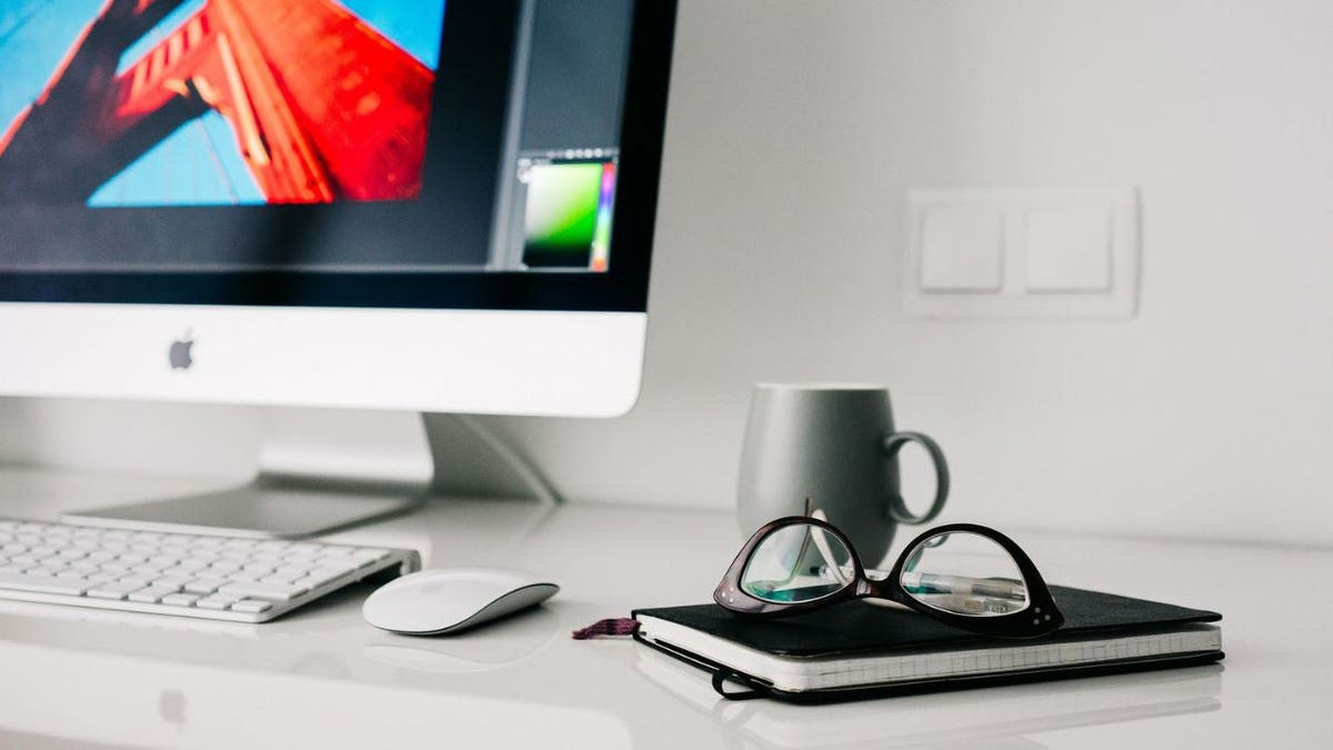 Mug, eyeglasses and notebook on desk near computer monitor