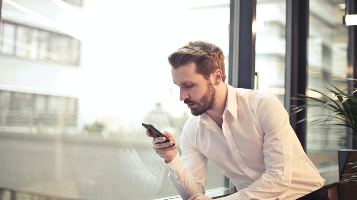 Man looks at phone while working at an office