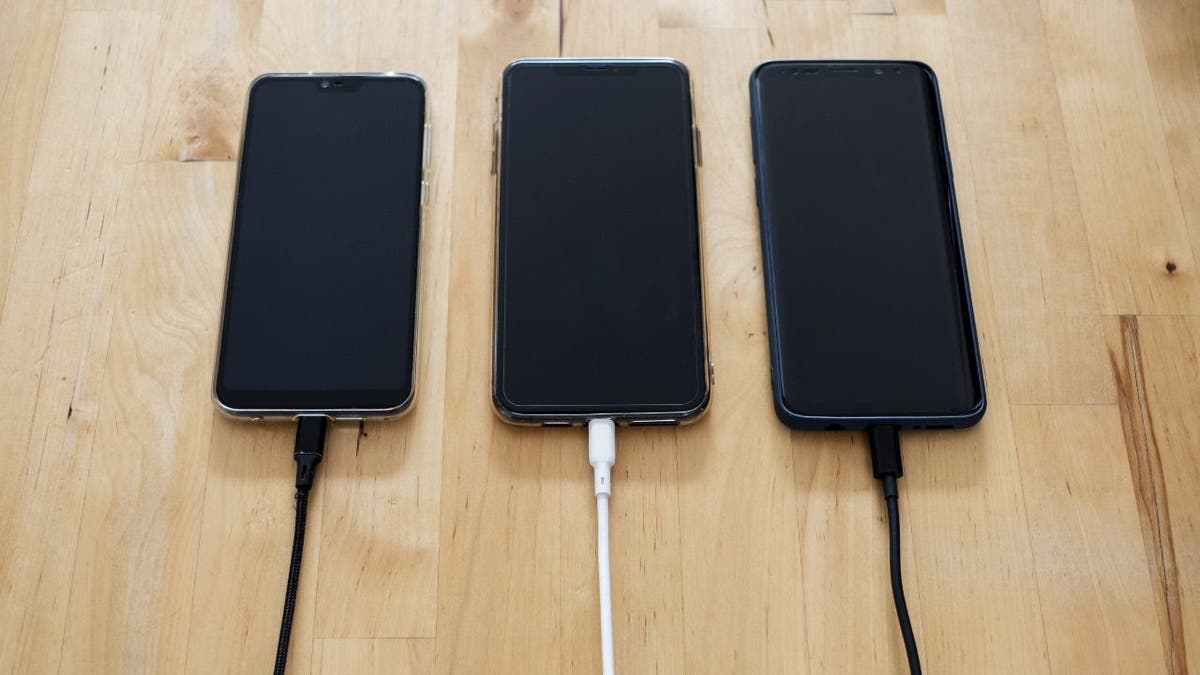 Three iPhones with dark screens plugged in