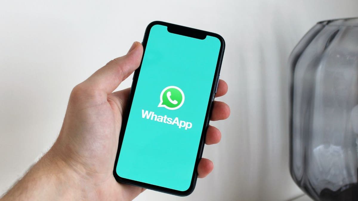 Person holds iPhone showing the Whatsapp logo