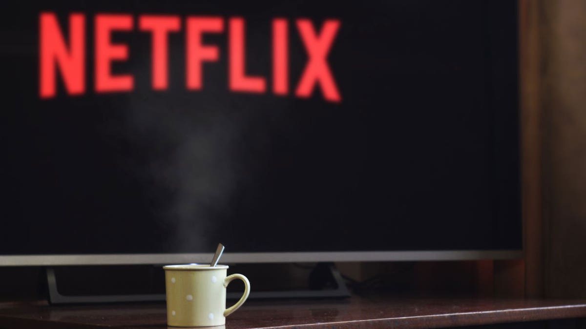 Photo of a mug in front of a TV with the Netflix logo.