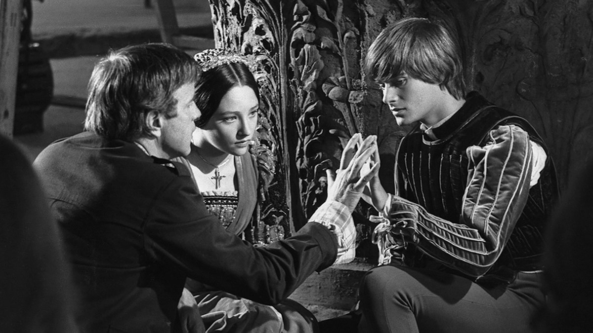 Black and white photo of Franco Zeffirelli directing Olivia Hussey and Leonard Whiting in "Romeo and Juliet"