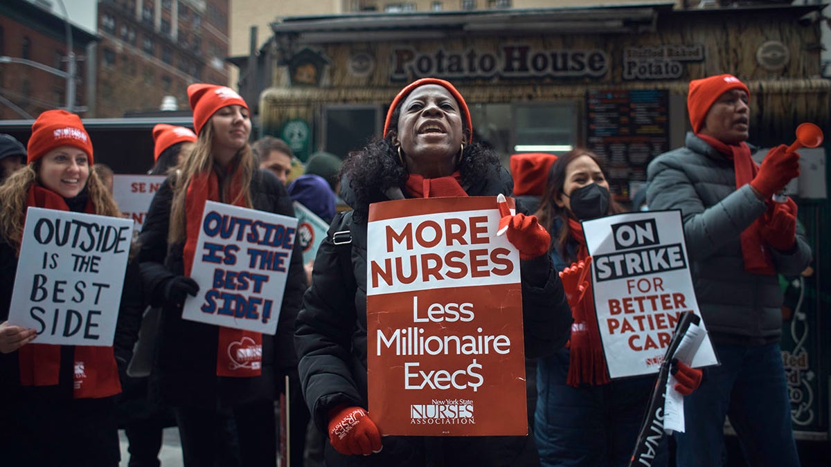 nurse holds sign demanding less million execs