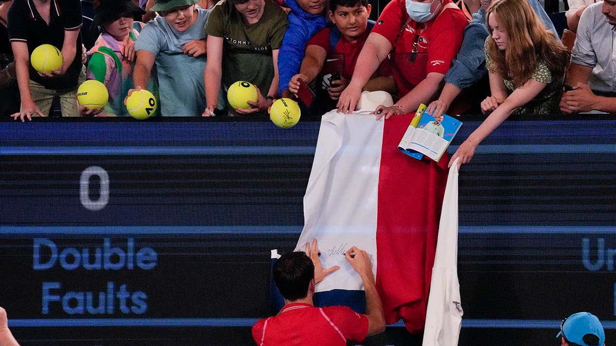 Daniil Medvedev signs a Russian flag at the Australian Open
