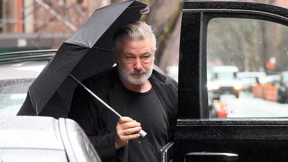 Man with umbrella gets back in to his car