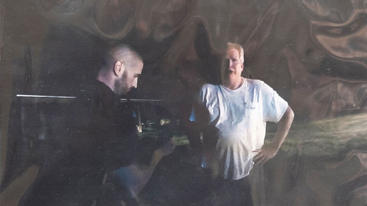 Evidence photos of a man wearing a white t-shirt speaking to a police officer.