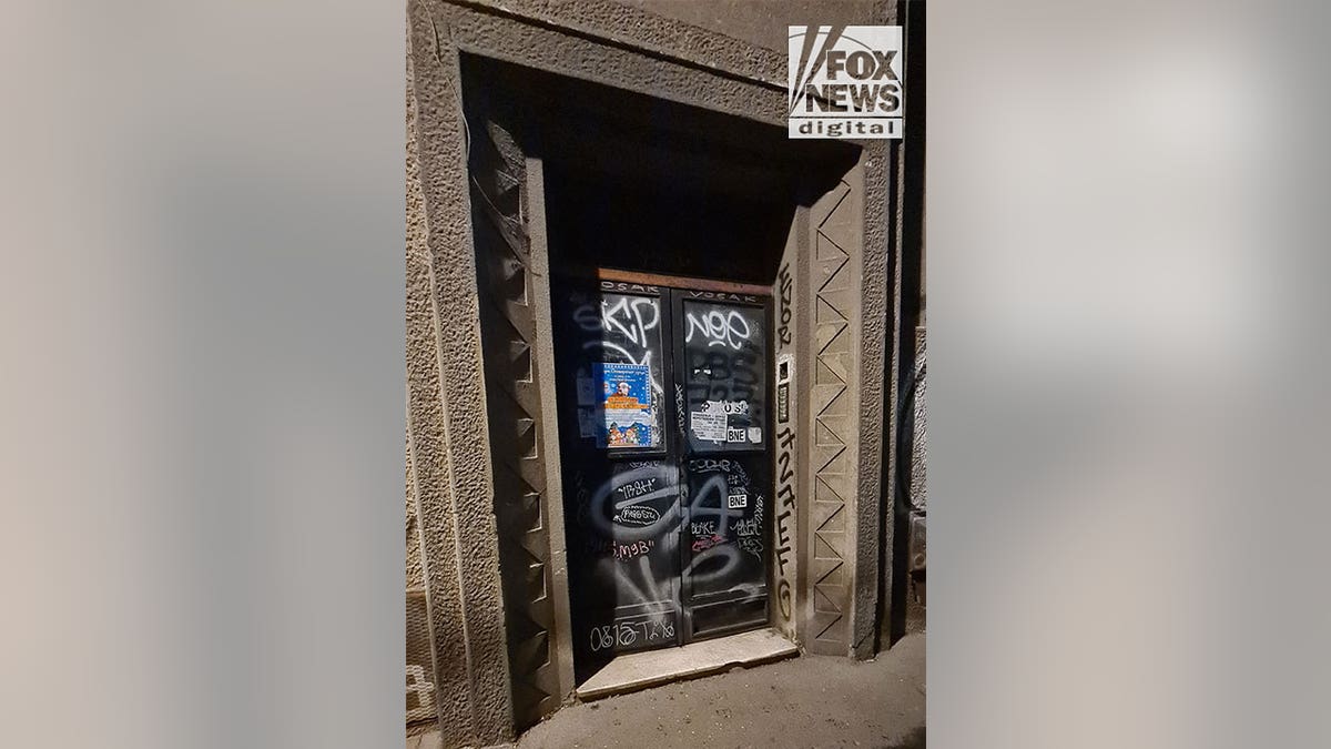 Apartment building entrance in an urban setting with graffiti on the doors