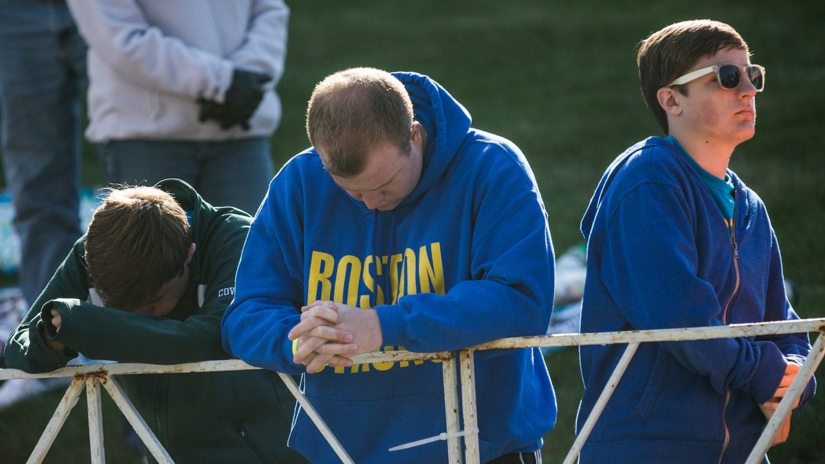 People bow their heads during a moment of silence prior to the start of the Boston Marathon