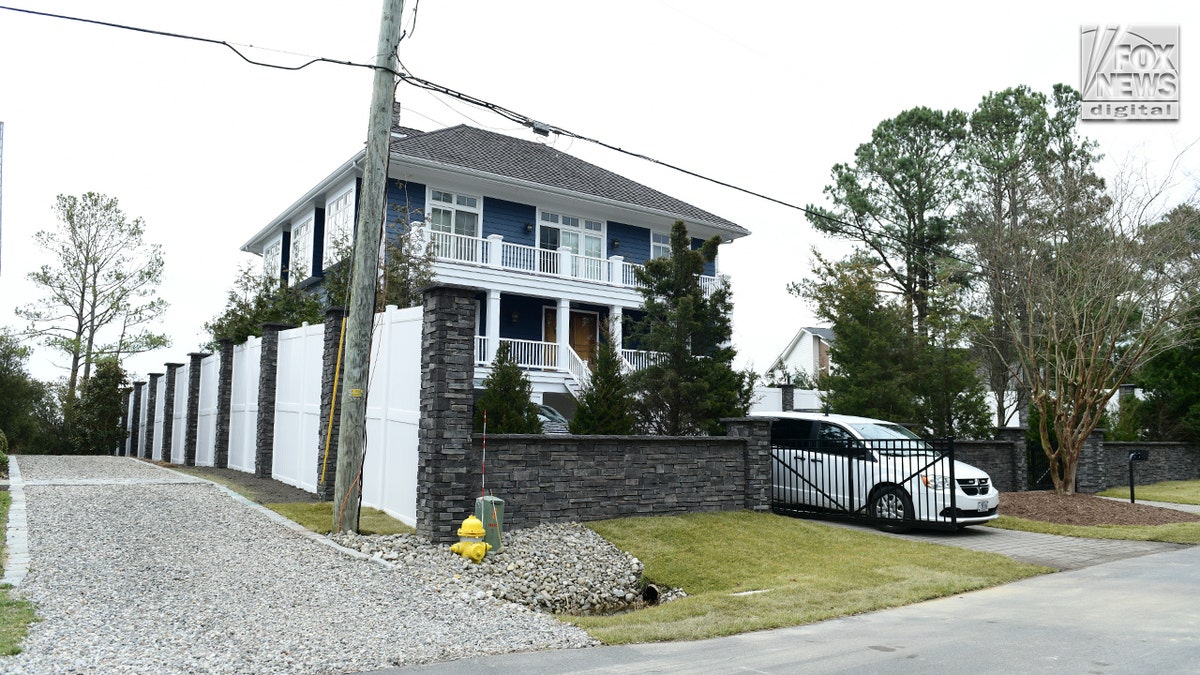 A wooden and stone fence surrounds a blue house.