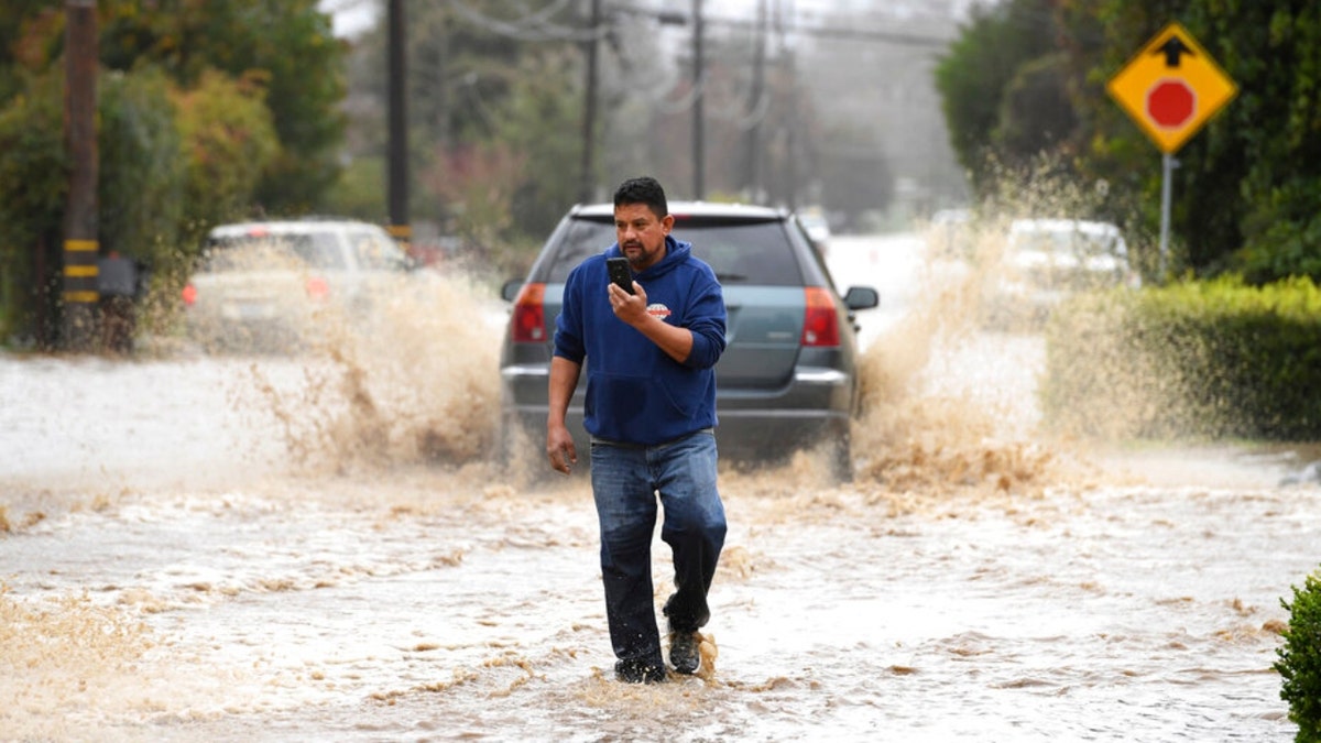 A resident walks on a flooded road