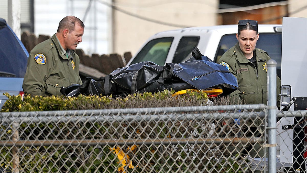 Photo of law enforcement rolling out one of the victims in a body bag.