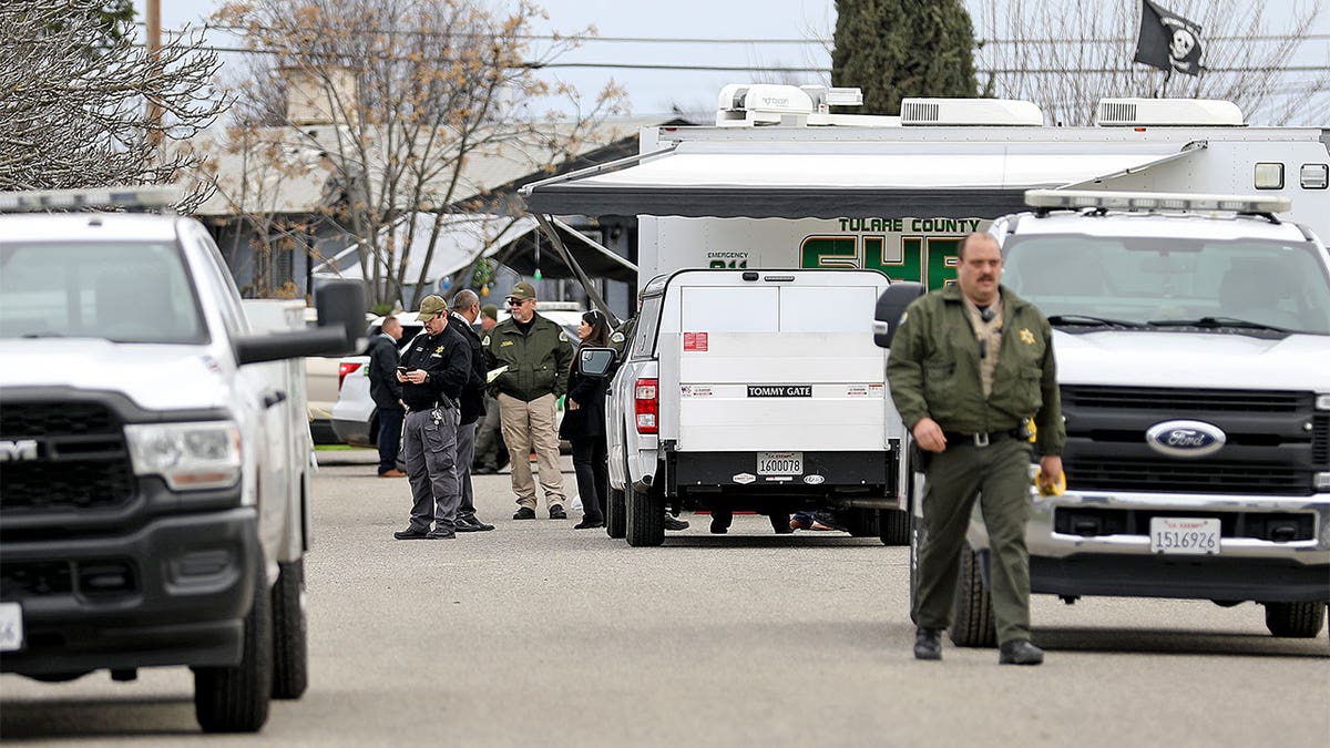 Sheriffs standing outside of the home belonging to a family that was murdered.