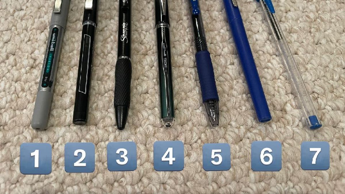 Seven pens lined up on rug