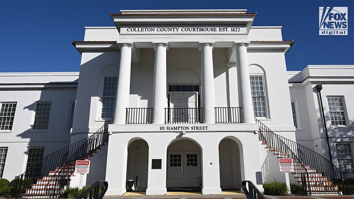 The front of a white courthouse with four large columns, a staircase on either side leading up to a grand entrance.