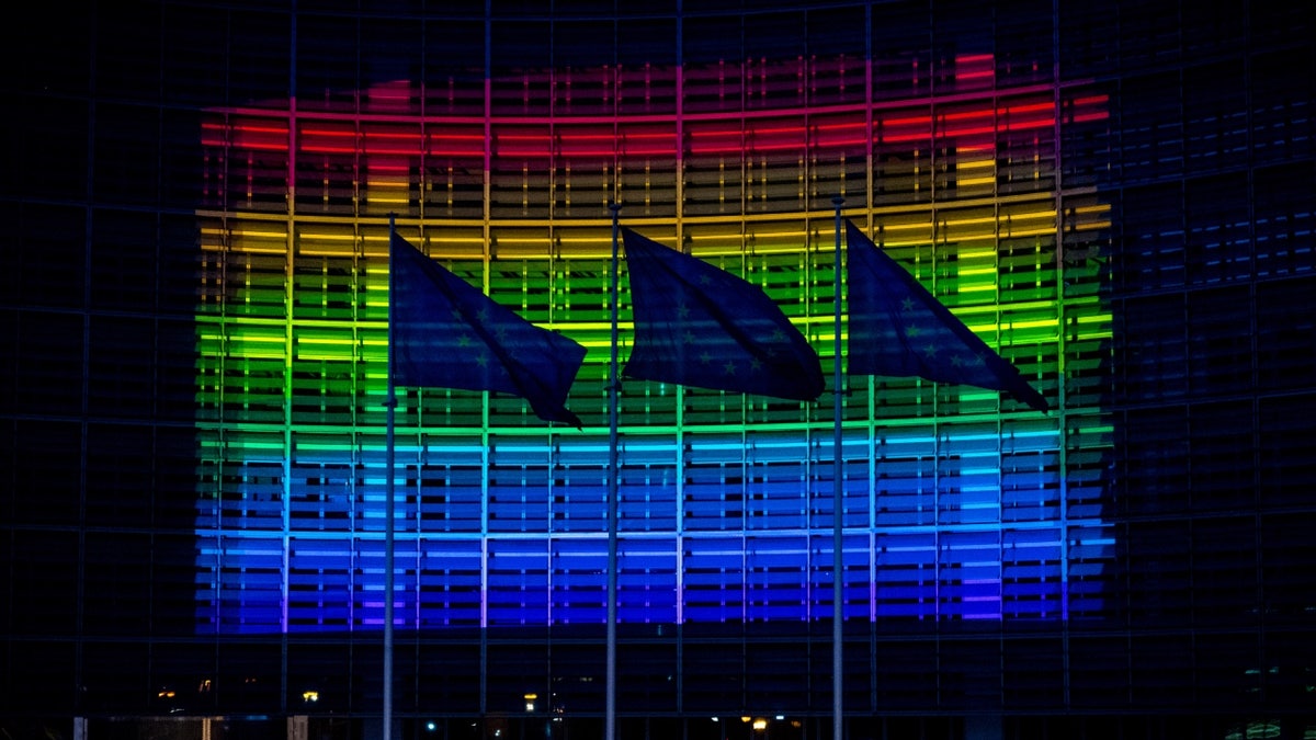 European Commission HQ with flags, lit up in rainbow colors