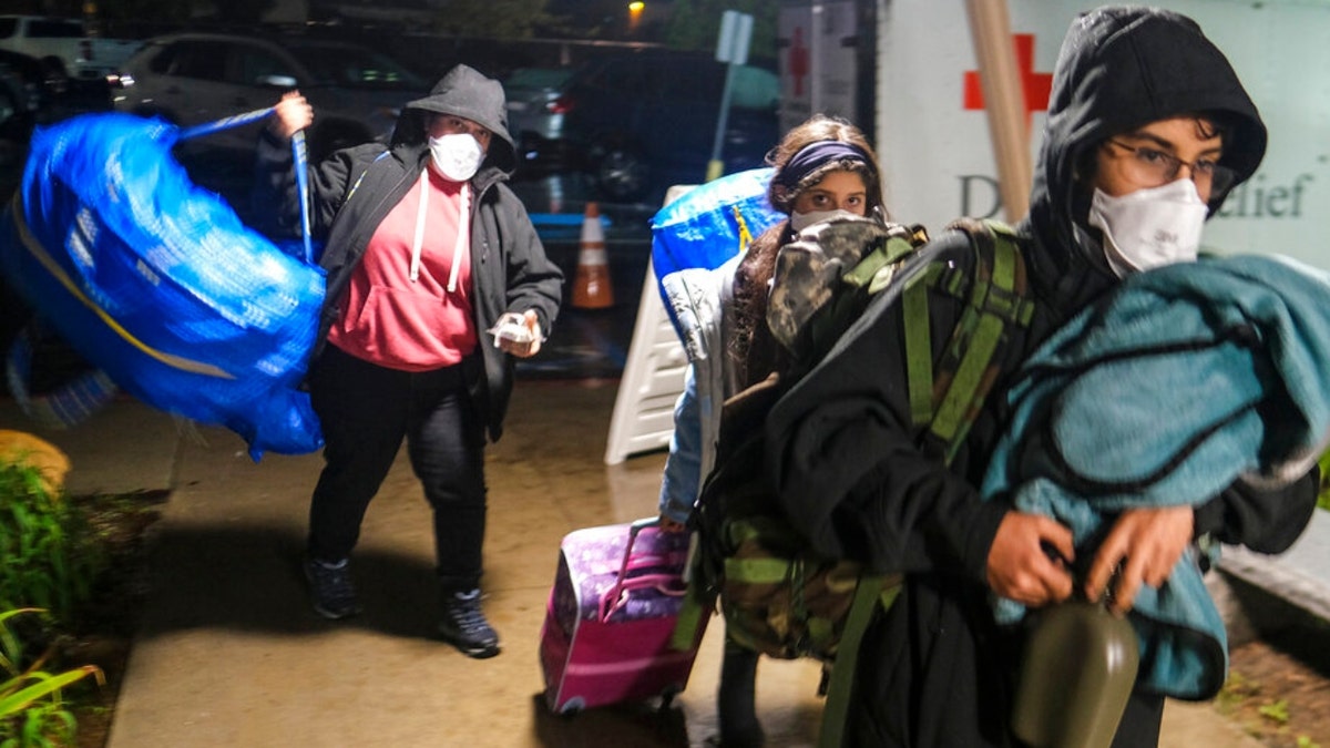People carrying their belongs arrive at an evacuation center