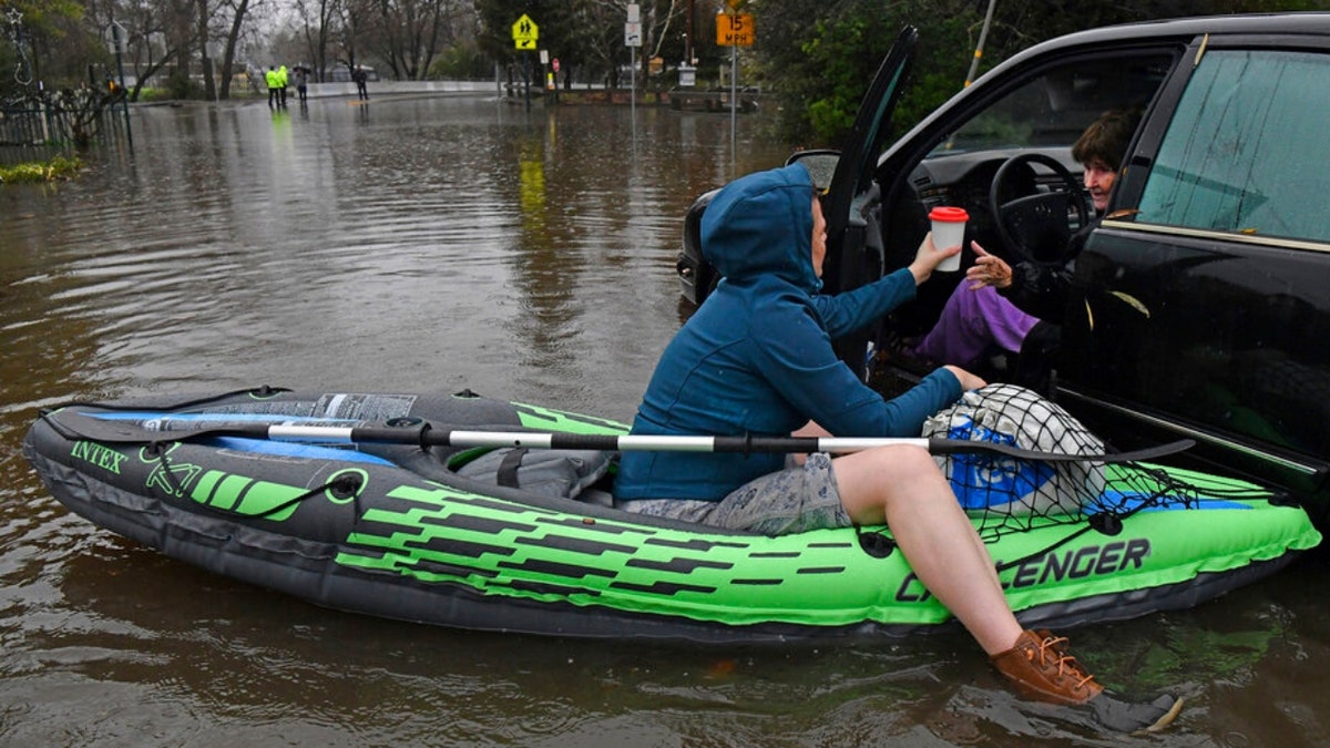 A woman trapped in a vehicle amid flooding in Pleasant Hill, Calif. is handed a cup of tea by a nurse in a raft